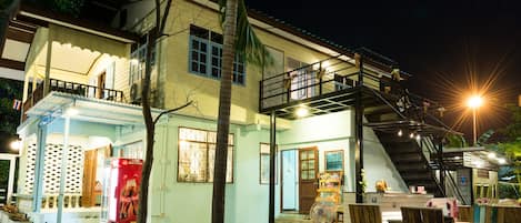 A two-story building with a balcony, outdoor seating area, and a staircase leading to the upper floor.