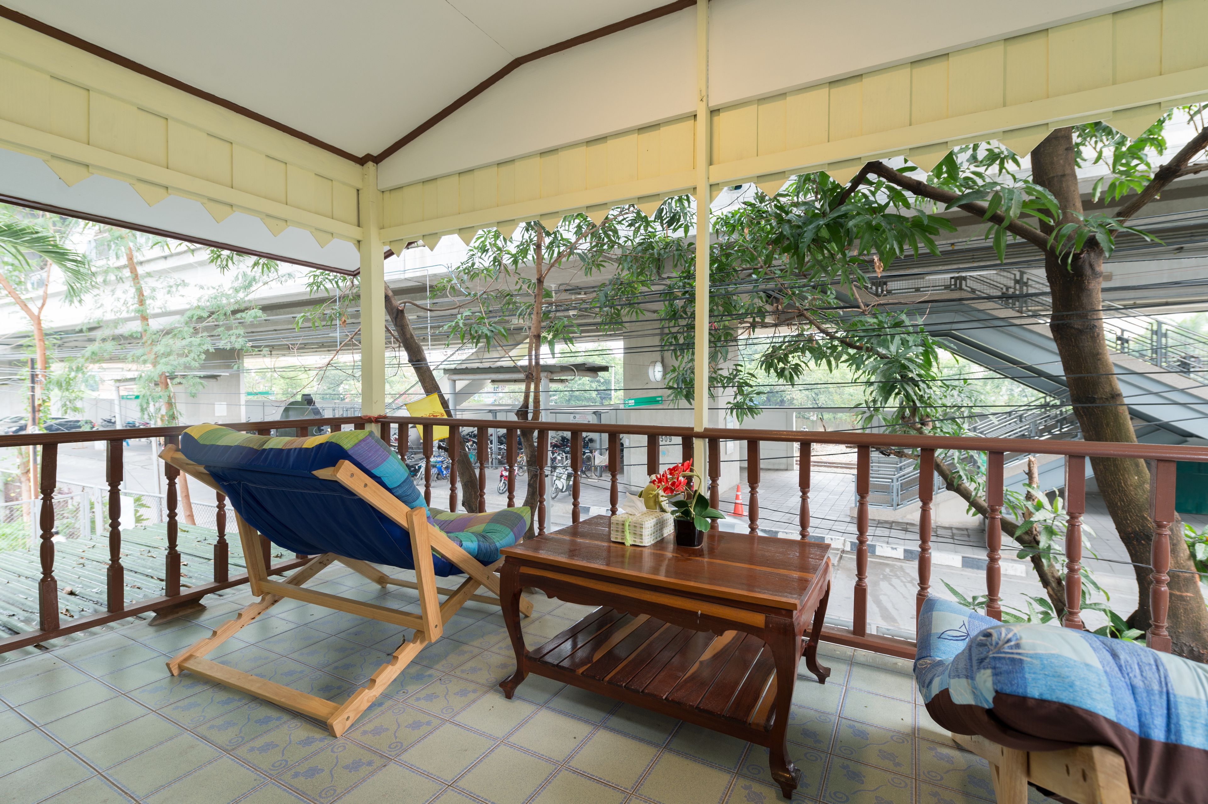 A covered balcony with wooden furniture, a table, and a chair.