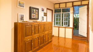 Un meuble en bois doté de plusieurs tiroirs, une fenêtre donnant sur un paysage verdoyant et une porte menant à l’extérieur.