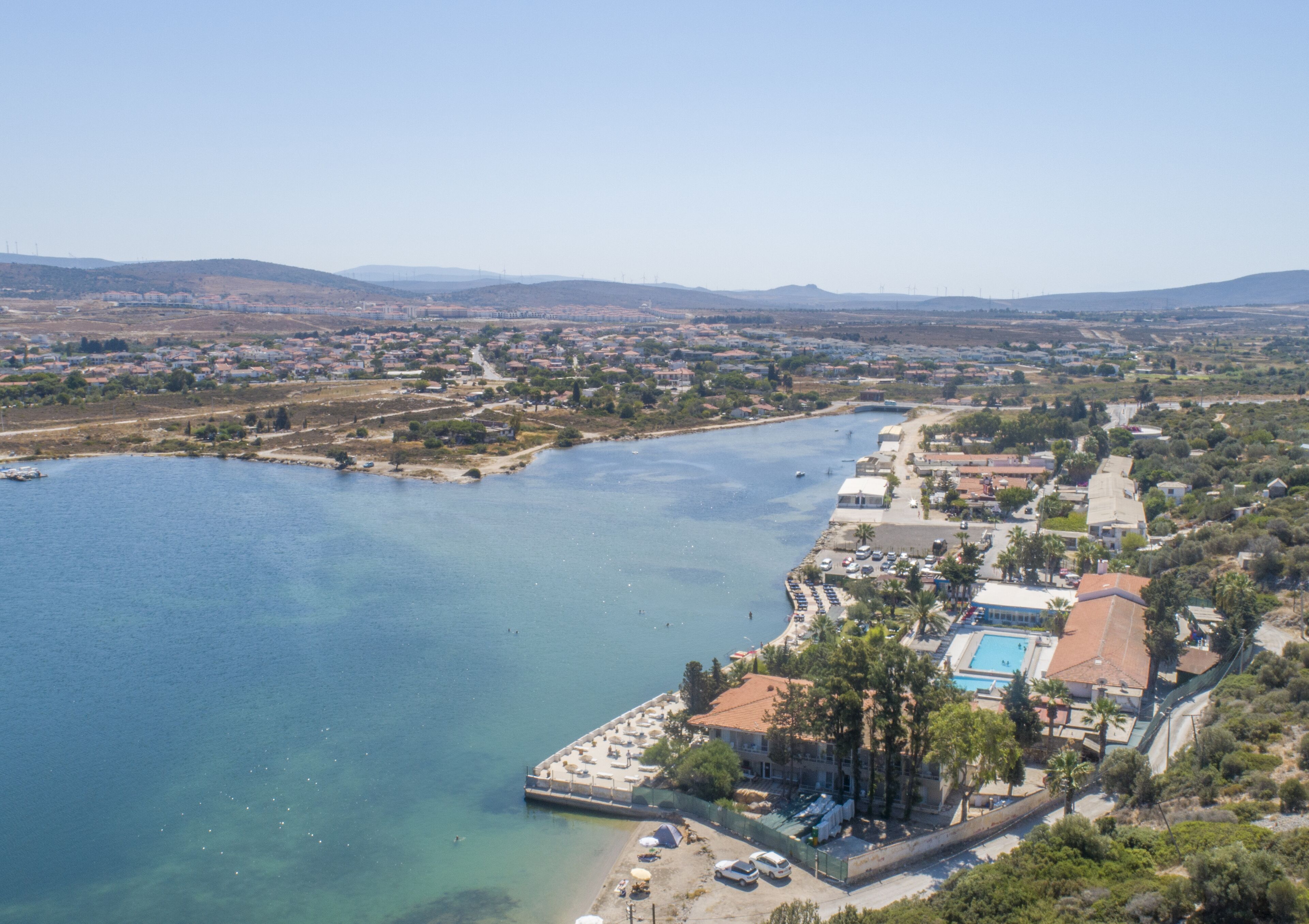 An aerial view of a coastal town with a marina, a swimming pool, and residential buildings.