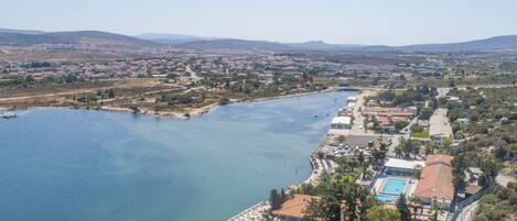 An aerial view of a coastal town with a marina, a swimming pool, and residential buildings.