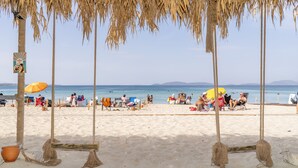 A beach with palm trees, beach chairs, and umbrellas. - Sifne Thermal Otel (Cesme)