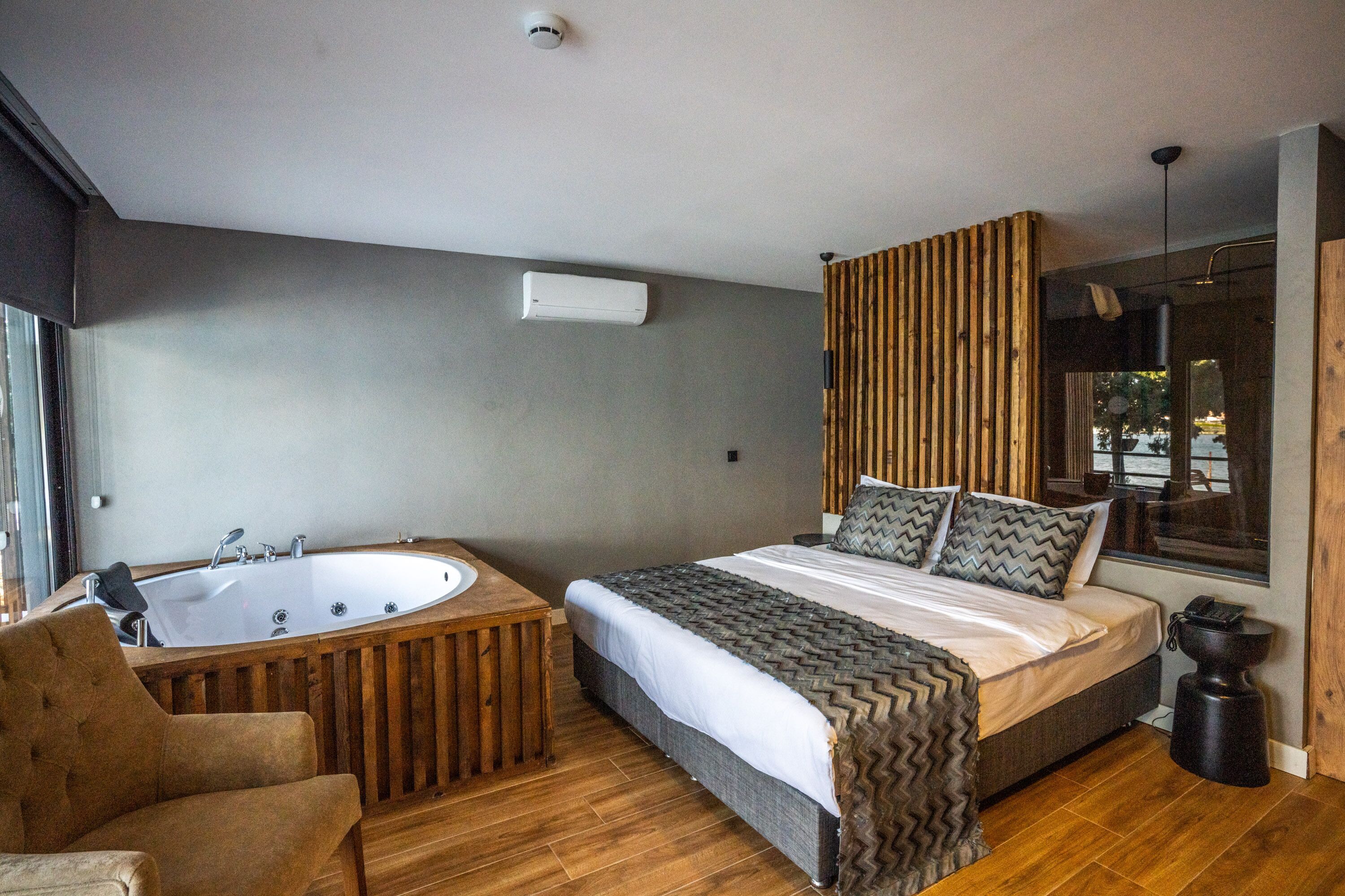 Un dormitorio moderno con una cama grande, una bañera de madera y un ventanal con vistas.