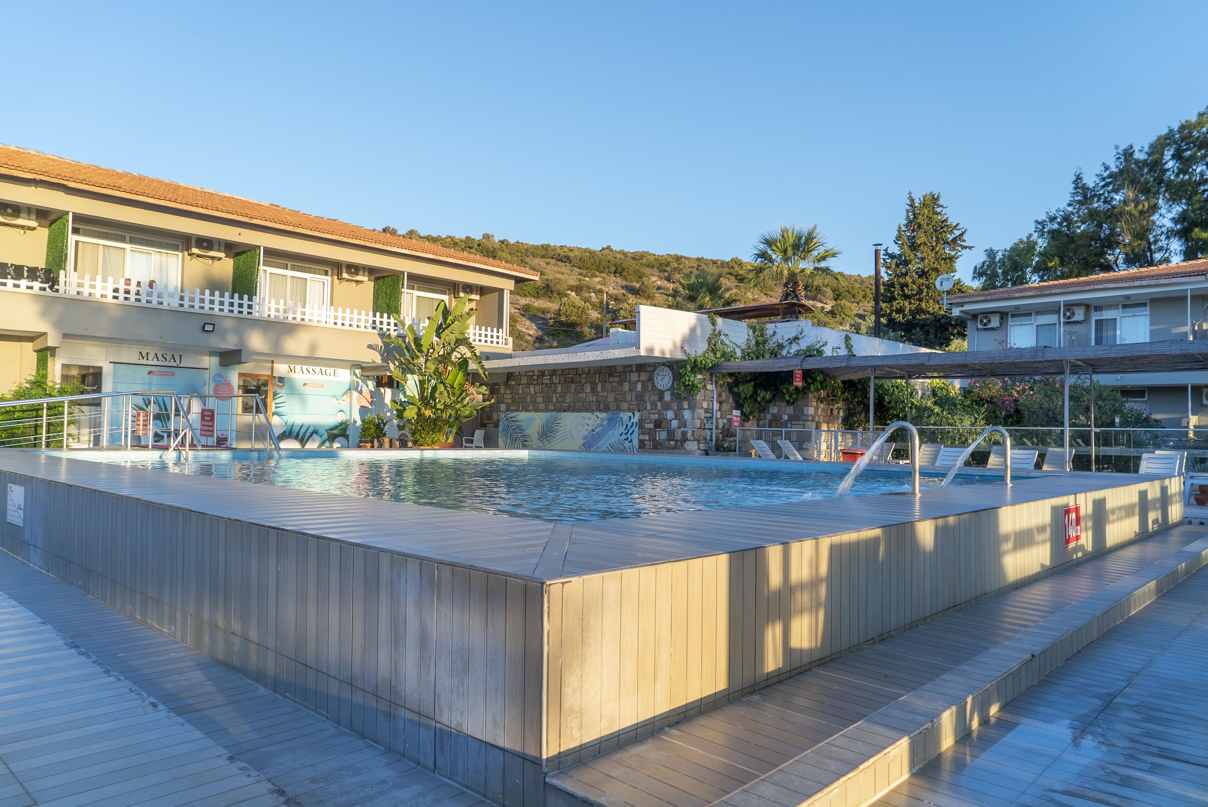 Una piscina con cubierta de madera, un centro de masajes y un edificio con balcón.