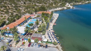 An aerial view of a coastal resort with a swimming pool, beachside lounge, and parking area. - Sifne Thermal Otel (Cesme)