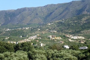 Un paisaje montañoso con edificios dispersos, probablemente una zona rural o semi-rural.