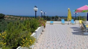 A terrace with tiled flooring, outdoor seating, and a view of the landscape. - Pinelopi Apartments (Apokoronas)