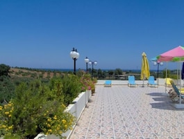Una terraza con suelo de baldosas, mobiliario exterior y vistas al paisaje.