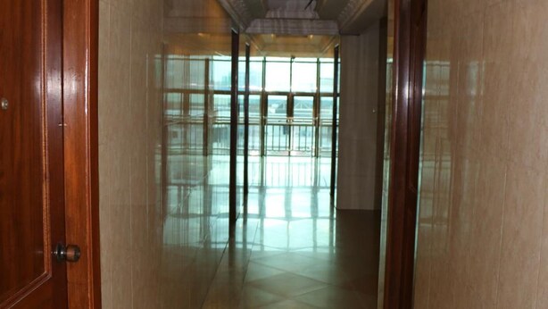 A hallway with marble floors and wooden doors, leading to a bright room with large windows. - Relax Guesthouse (Phnom Penh)