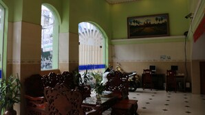 A spacious lobby with a high ceiling, arched windows, and a painting on the wall. - Relax Guesthouse (Phnom Penh)