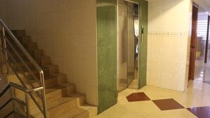 A hotel lobby with a staircase, a glass elevator, and a patterned floor. - Relax Guesthouse (Phnom Penh)