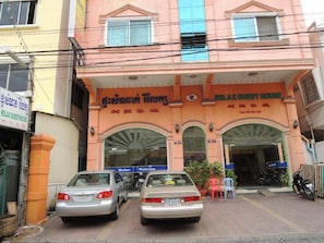 A building with a sign reading "Relax Guest House" and another sign in a different language. There are two cars parked in front, and a motorcycle is parked to the side. - Relax Guesthouse (Phnom Penh)