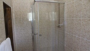 Een douche met glazen wanden, een betegelde muur en een houten deur.