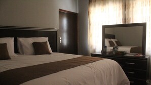 Een hotelkamer met een groot bed, een nachtkastje, een spiegel en een deur.