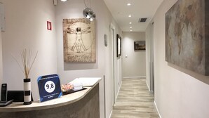 Uma área de recepção de hotel com design moderno, incluindo um balcão de atendimento, um painel com prêmios de avaliação de hóspedes e obras de arte nas paredes.