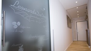 Corredor moderno de hotel com parede que apresenta nomes e imagens de frutas e grãos de café, indicando ênfase em ingredientes frescos.