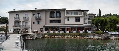 Un bâtiment situé au bord de l’eau, avec un restaurant au rez-de-chaussée, doté d’une terrasse et d’un quai.