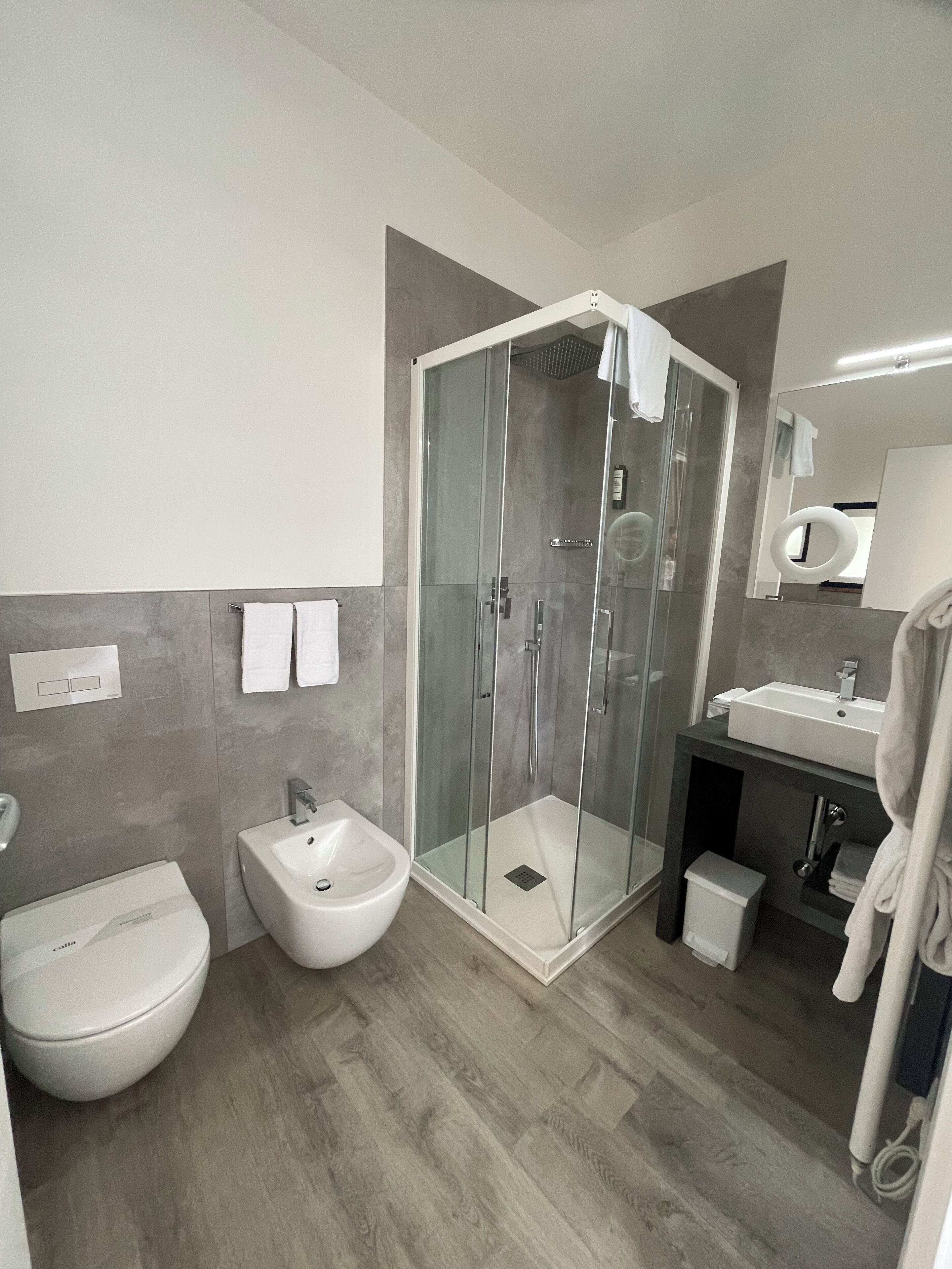 A modern bathroom with a glass-enclosed shower, a bidet, a toilet, and a sink.