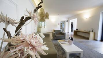 Ein modernes Wohnzimmer mit einer Eckcouch, einem Couchtisch und dekorativen Zweigen mit Blumen.