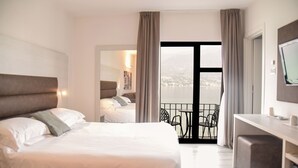 Una habitación de hotel con una cama grande, un escritorio y un balcón con vistas.