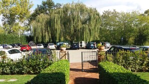 A parking lot with various cars, a gated entrance, and well-maintained hedges. - Oasi del grillo (Castelnuovo Berardenga)