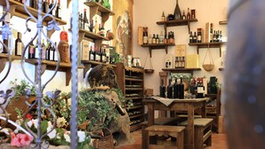 A wine shop with wooden shelves and tables, displaying various bottles and a mural on the wall. - Hotel Ristorante S'Astore (Benetutti)