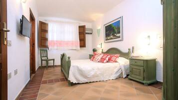 A bedroom with a bed, a chair, a nightstand, and a television.