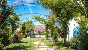 A garden pathway leading to a building with a tiled roof, surrounded by lush greenery and flowering plants. - Hotel Ristorante S'Astore (Benetutti)