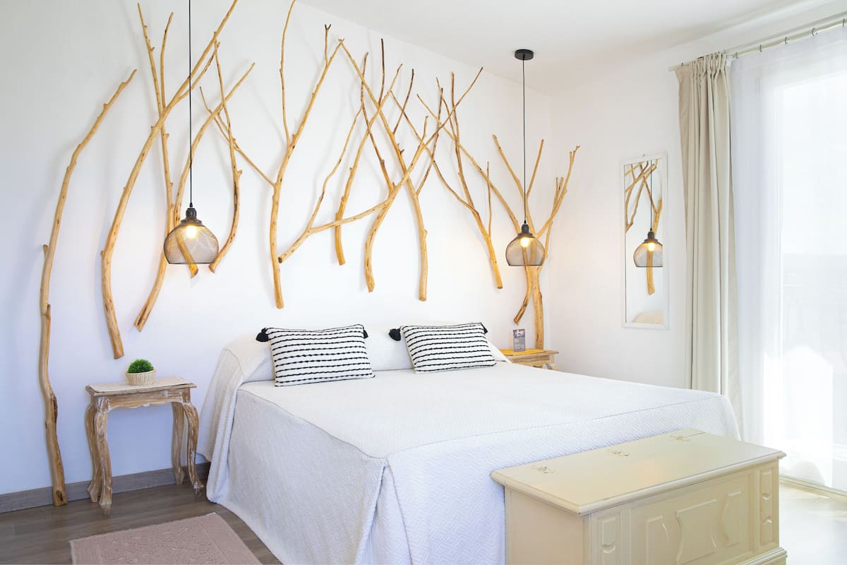 A bedroom with a large bed, two bedside tables, a small side table, and a bench.