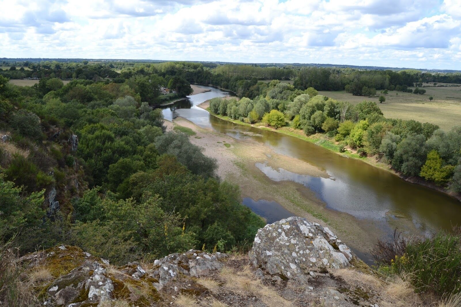 A river winding through a forested landscape with rocky outcrops in the foreground.