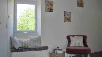 A room with a window seat, a red armchair, and wall art.