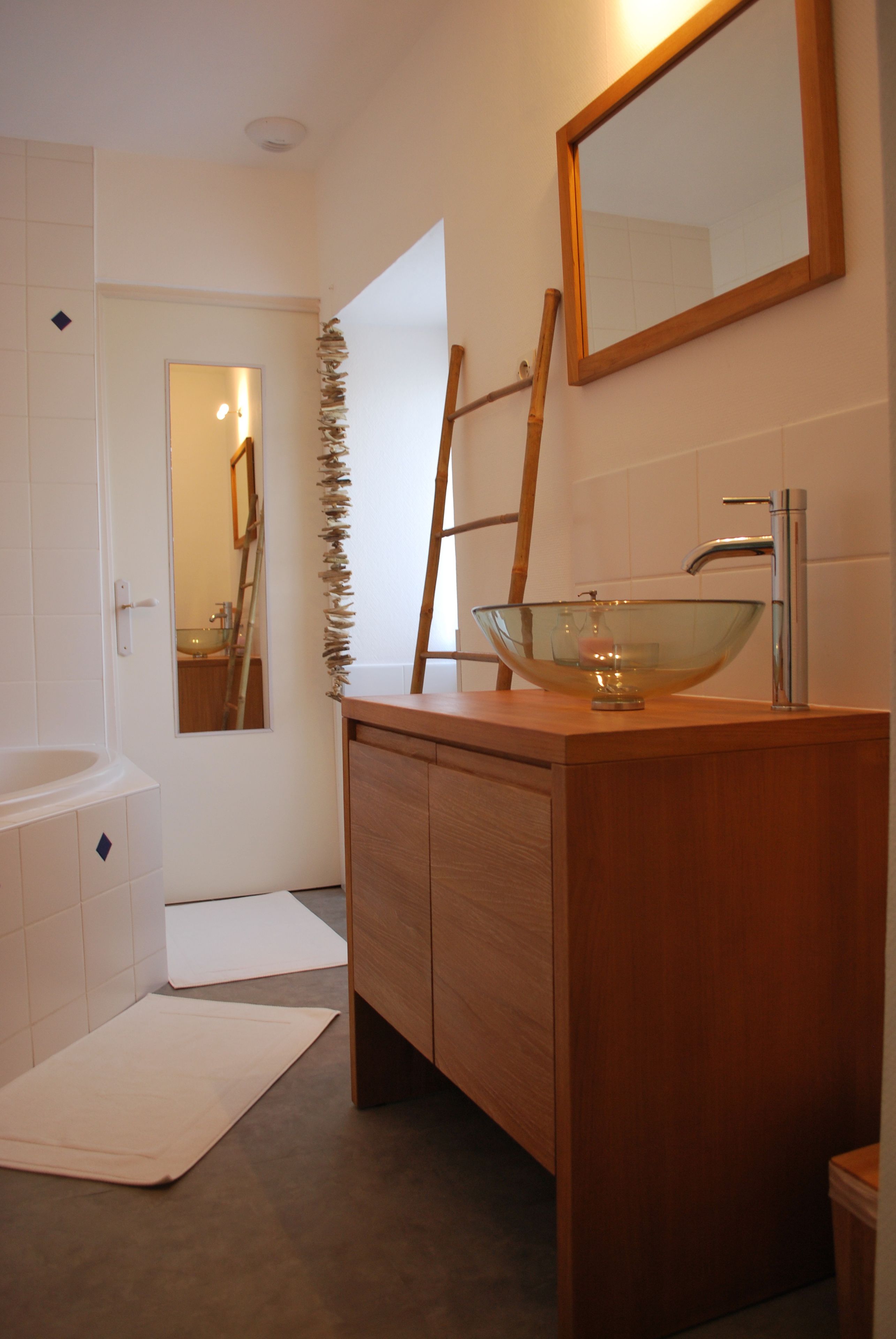 Une salle de bain moderne avec un lavabo en forme de bol en verre, un meuble-lavabo en bois et un miroir au-dessus du lavabo.