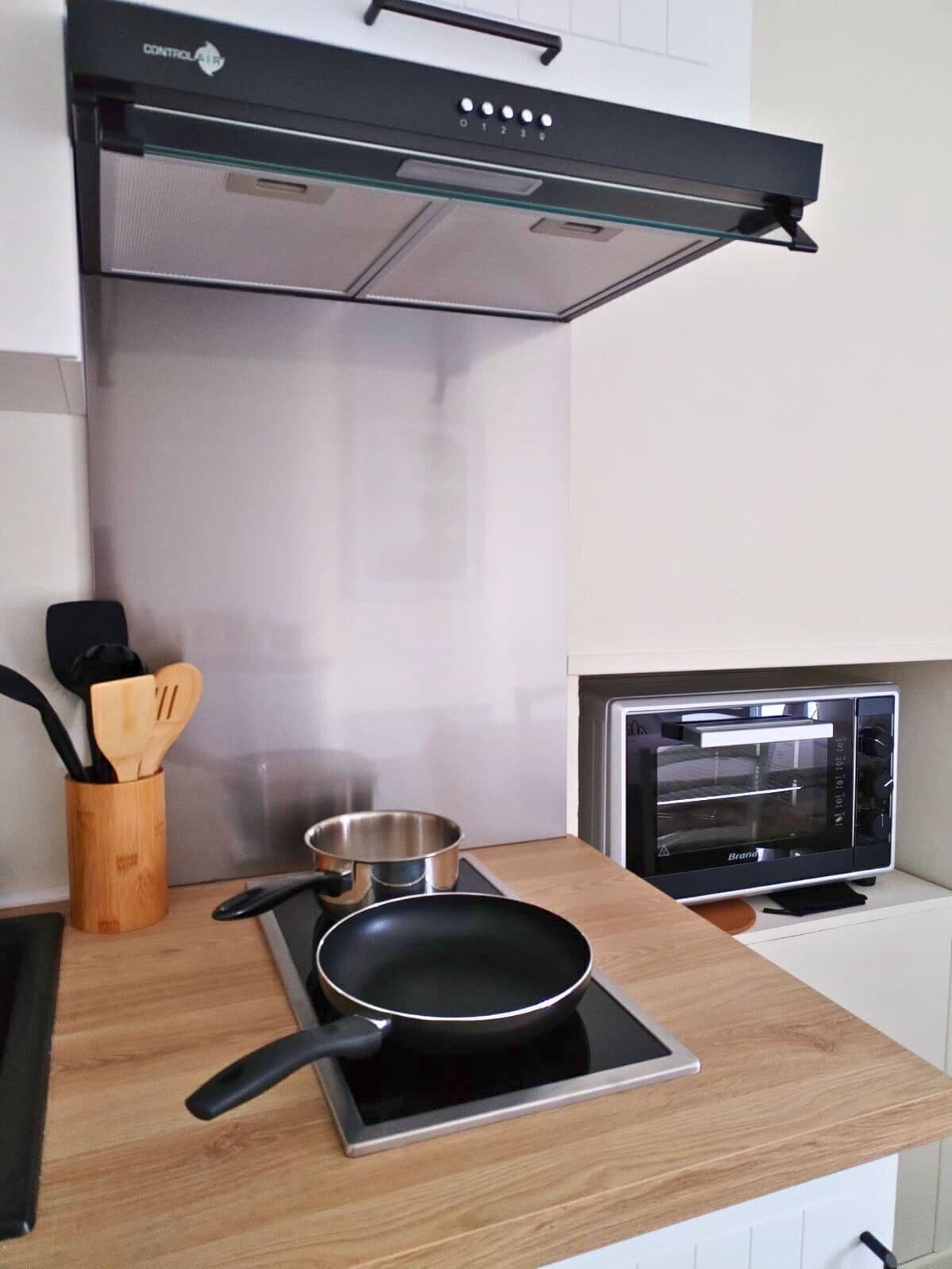 Een keuken met een inbouwfornuis, een toasteroven en een afzuigkap.