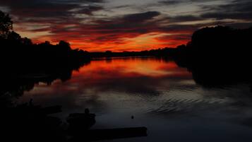 Una puesta de sol serena sobre un río tranquilo con barcos amarrados a la izquierda.
