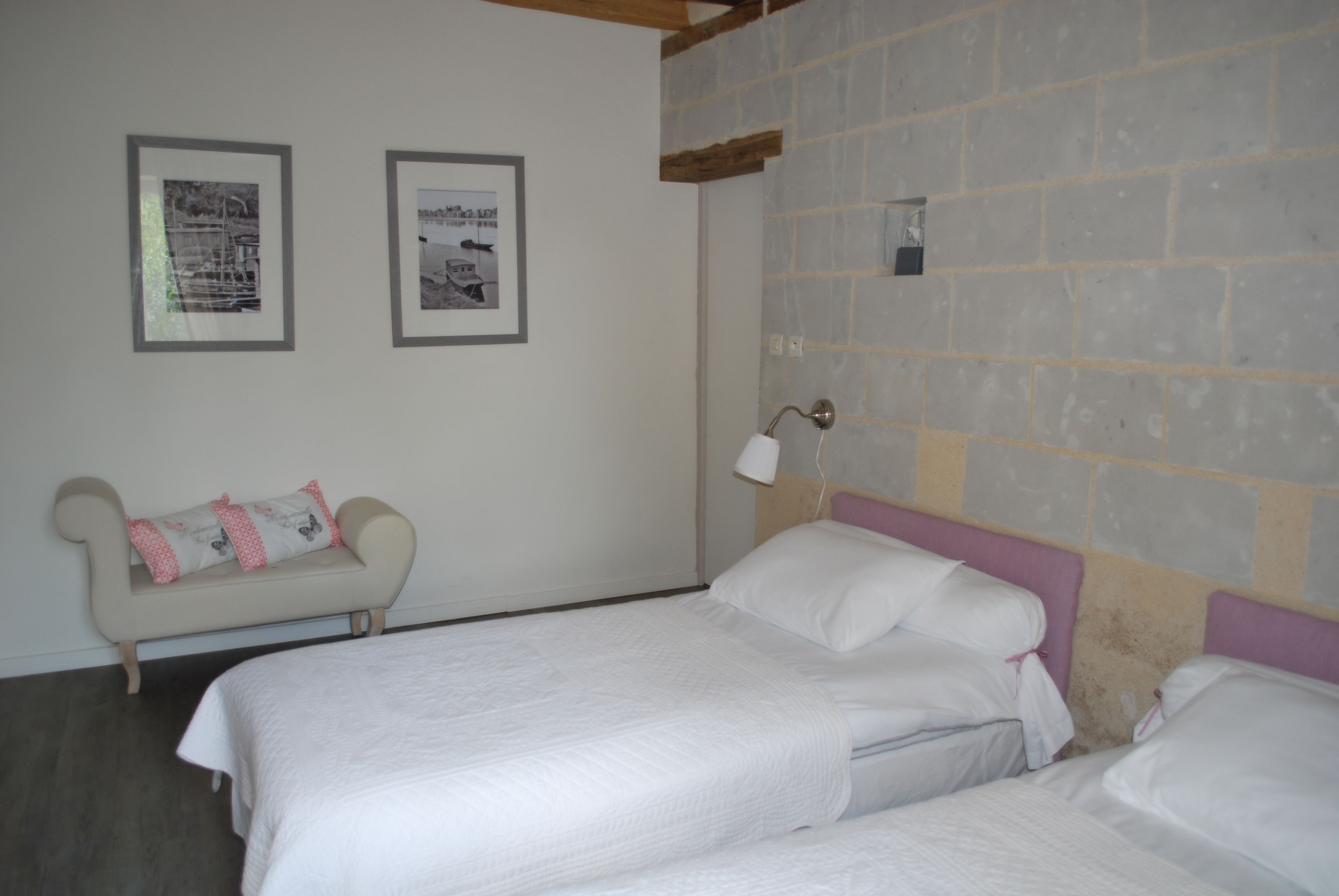 Une chambre avec deux lits, un petit canapé et deux tableaux encadrés accrochés au mur.