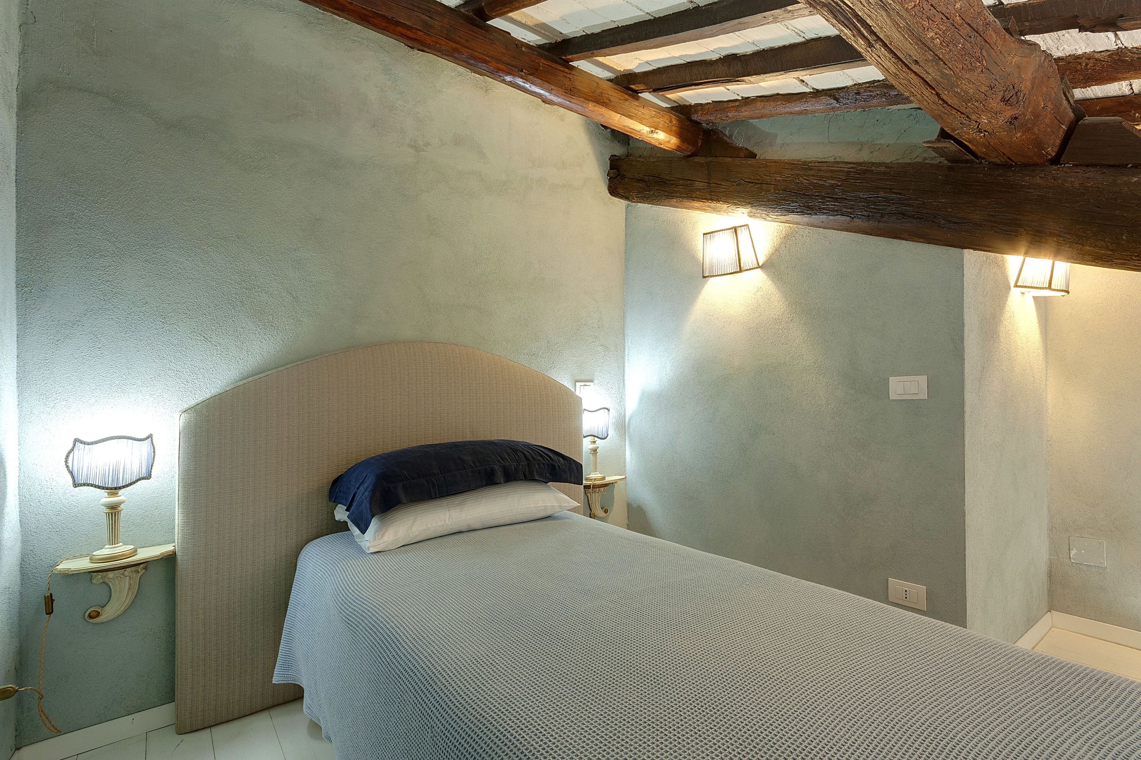 Un dormitorio con una cama, una mesita de noche y una lámpara de pared.