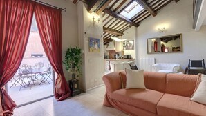 A living room with a sofa, a dining table with chairs, a potted plant, and a view of the outside. - LM Suite Spagna (Rome)