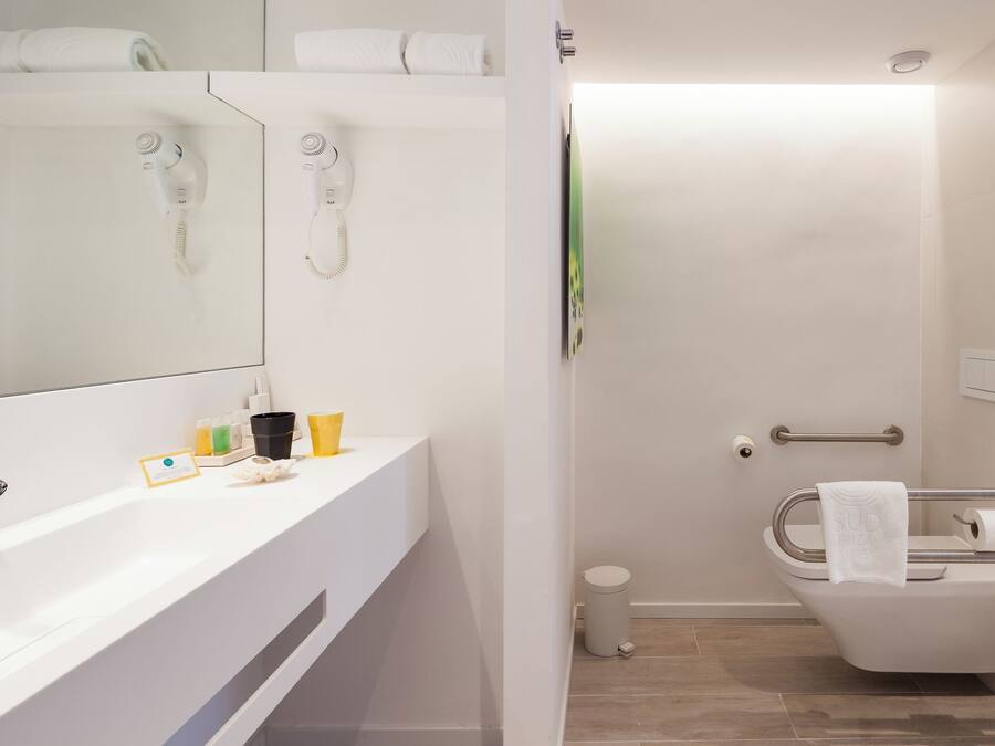 Une salle de bain moderne avec un meuble-lavabo blanc, un espace douche et des toilettes.