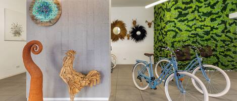 A modern interior with a concrete wall, wooden sculptures, and a green wall with foliage.
