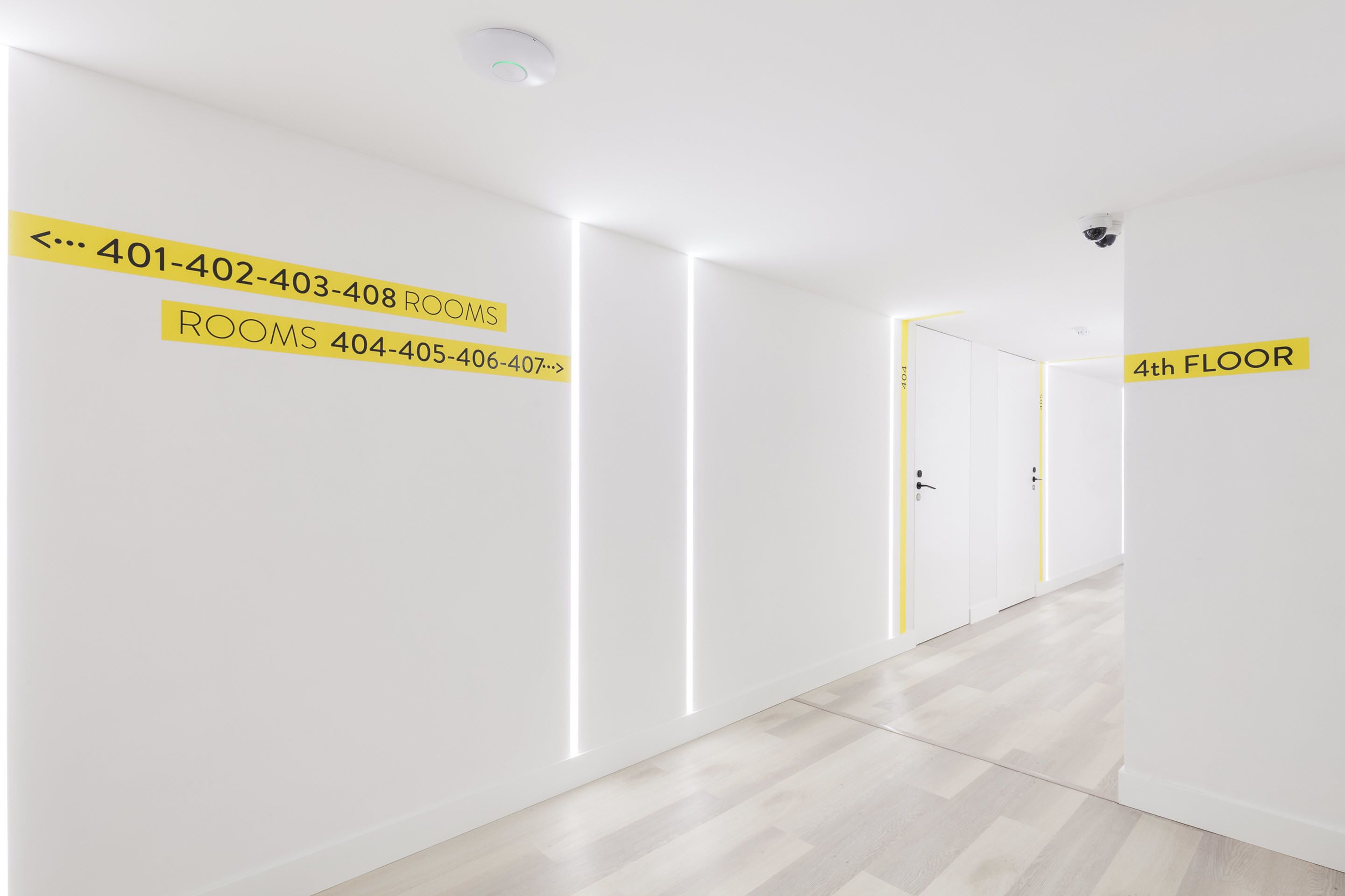 A hallway with directional signs indicating room numbers and a sign for the 4th floor.