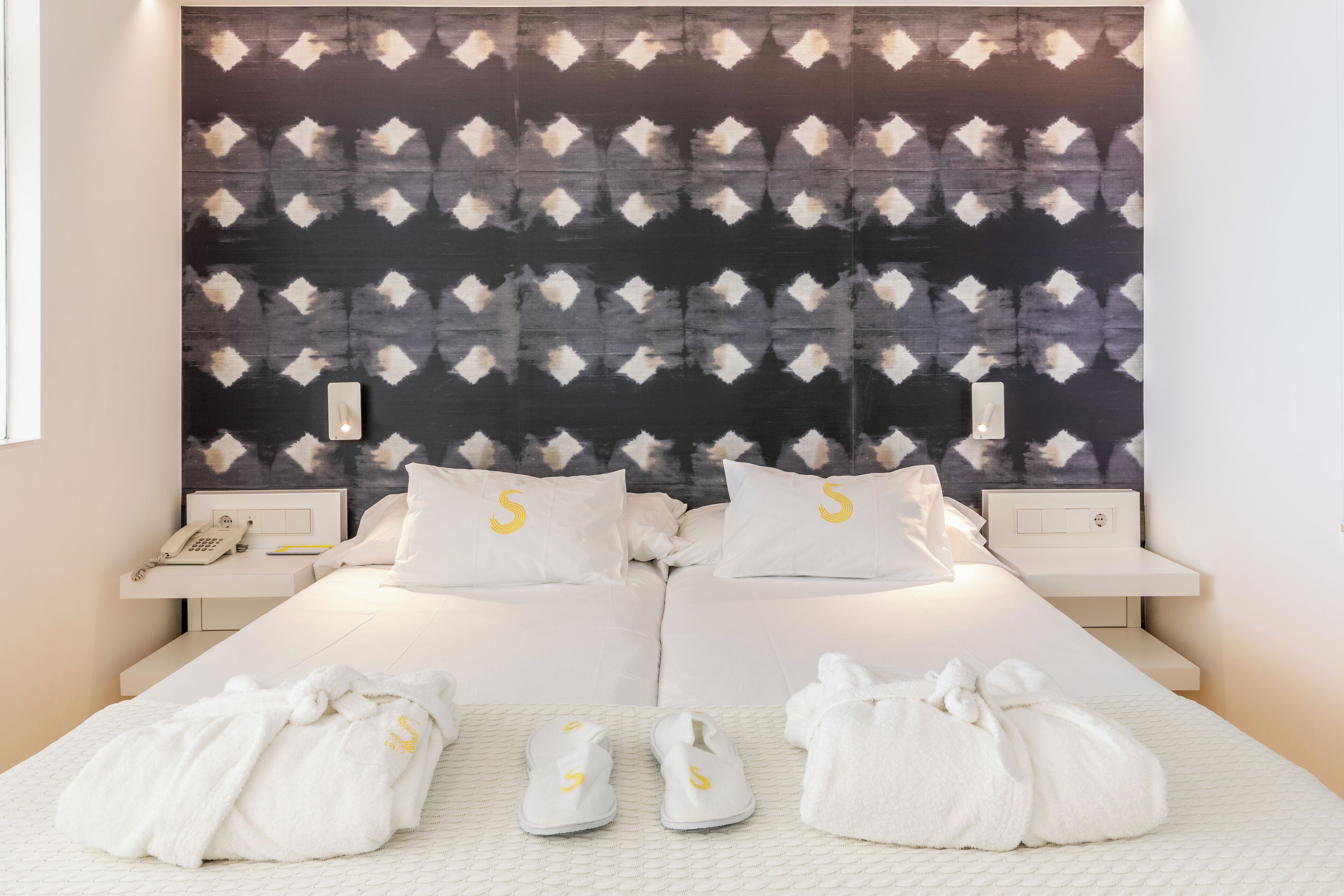 Una habitación de hotel con una cama, dos mesitas de noche, un teléfono y toallas.