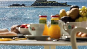 Una mesa con alimentos para el desayuno y vista al mar.
