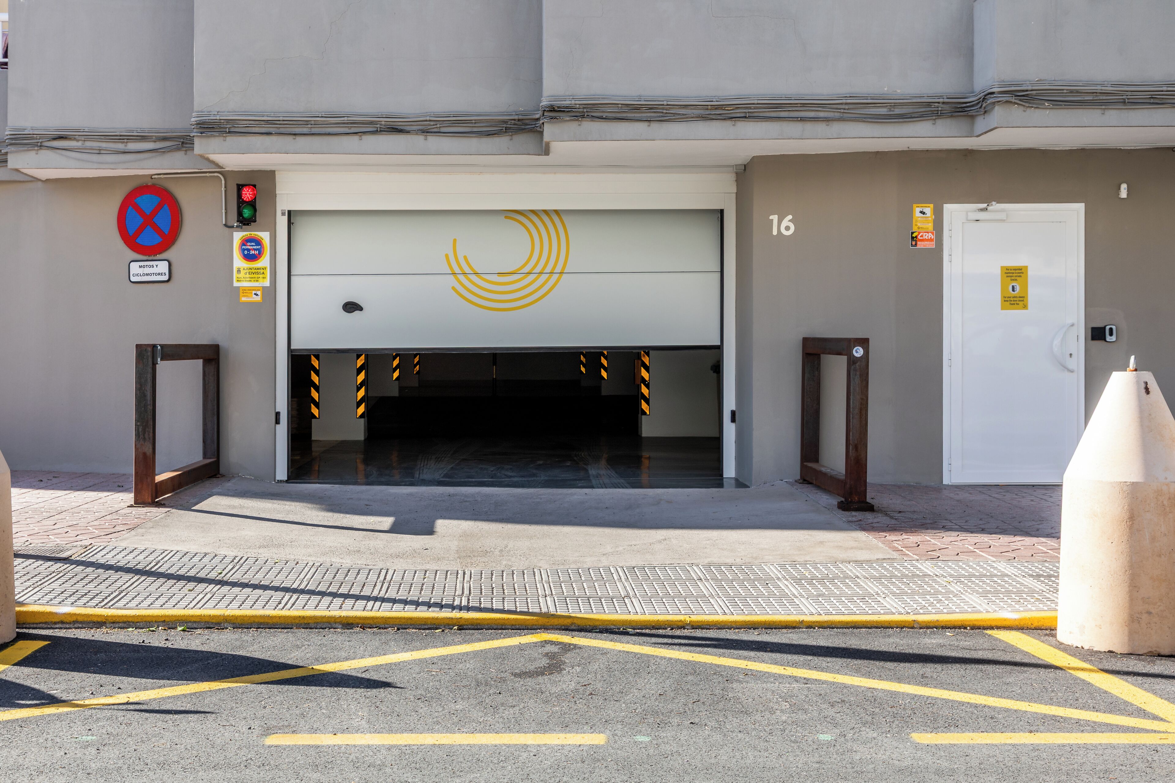 En hotelindgang med en garageport, et parkeringsforbudsskilte og en brandalarmering.