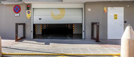 En hotelindgang med en garageport, et parkeringsforbudsskilte og en brandalarmering.