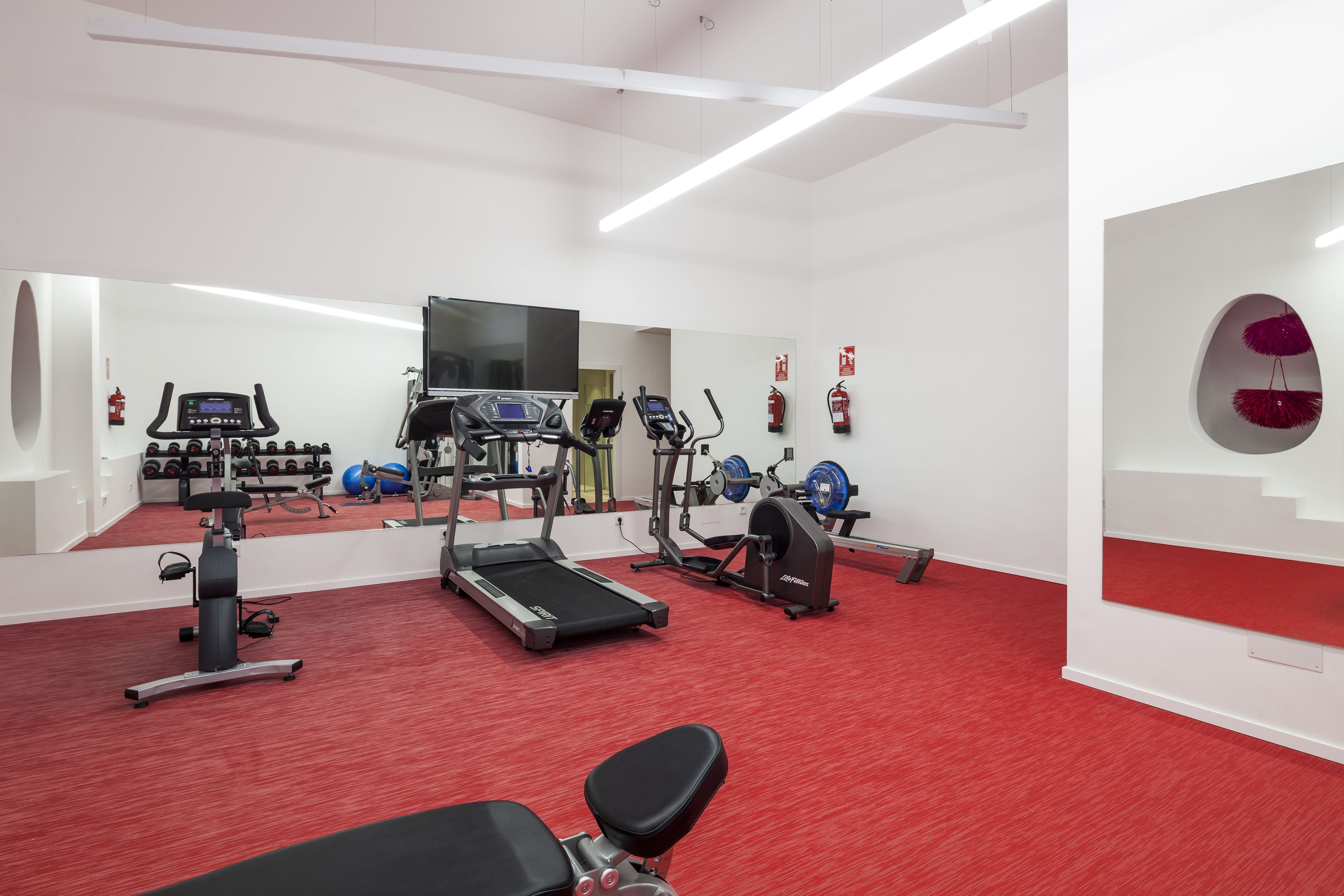 Une salle de sport équipée de tapis de course, de vélos elliptiques et de bancs de musculation.