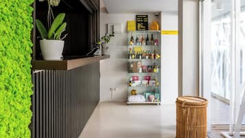 Un interior modern amb una paret verda, una taula de recepció, una prestatgeria per a vi i una cistella de vimet.