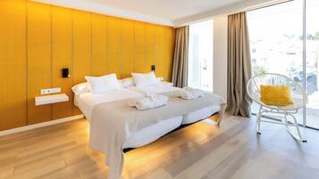 Habitación de hotel moderna con una cama grande, una pared de color amarillo brillante y vistas a la ciudad a través de amplias ventanas.