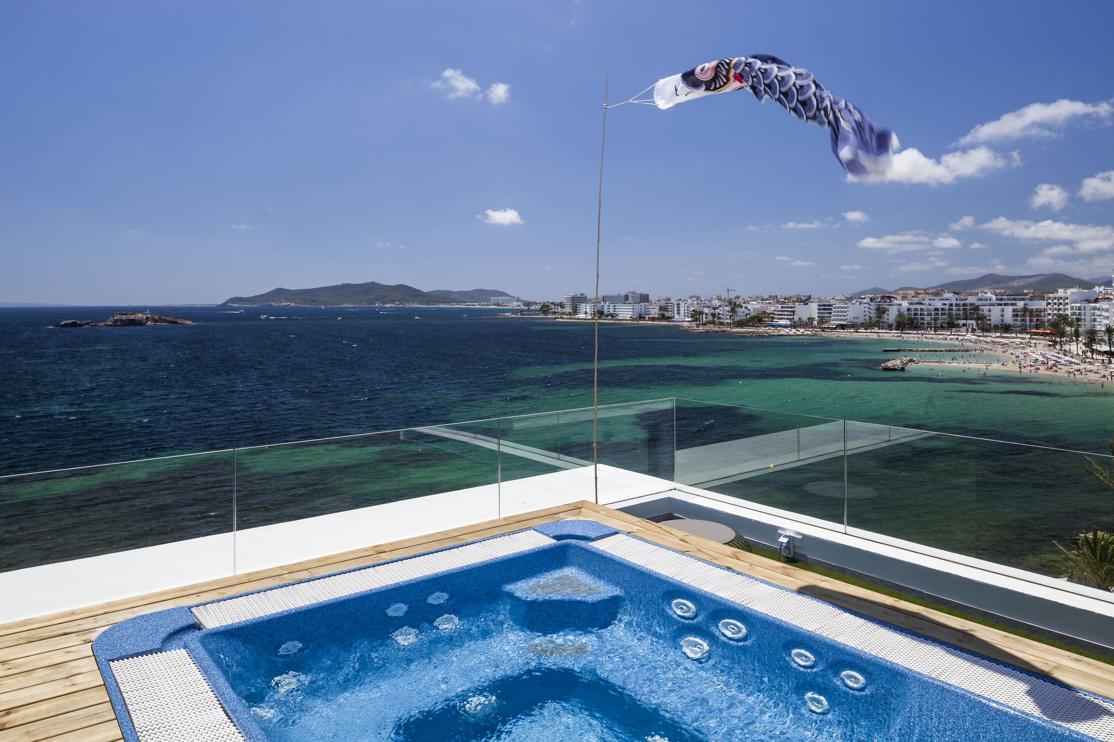 Een bubbelbad op een balkon met uitzicht op zee en een strand.