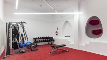 A gym with exercise equipment, dumbbells, and a bench.