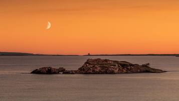 Água calma com um afloramento rochoso no centro.